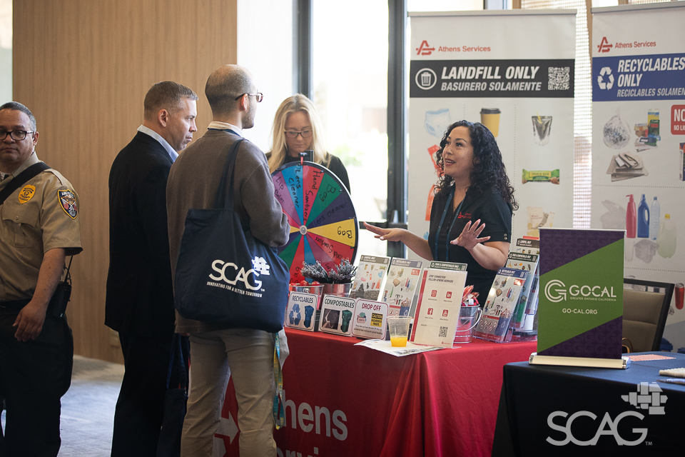 A group talks at an event booth with pamphlets and a multicolored wheel.
